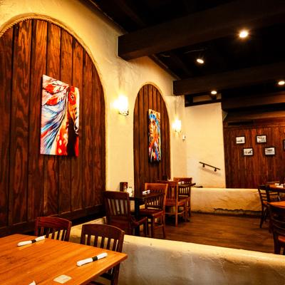 Restaurant interior with wooden wall panels, wooden tables, and colorful artwork.