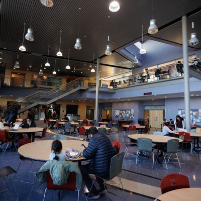 Two level dining hall with round tables and people dining.