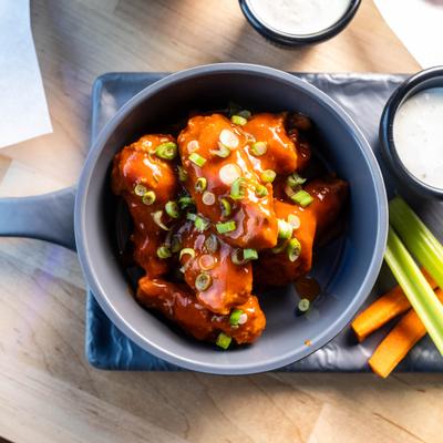 Cauliflower Wings topped with sauce, served with vegetable sticks and a dipping sauce.