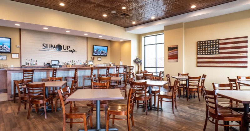 Chairs and tables in front of a bar, US flag on a wall