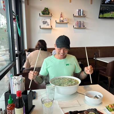 Guest with a large bowl of soup, holding large chopsticks.