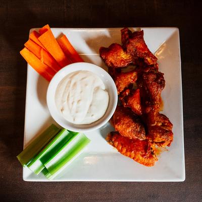 Buffalo wings served with a dip, celery and carrot sticks, top view