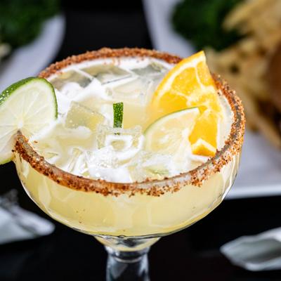 Cocktail with ice and citrus garnishes in a glass with a spiced rim..