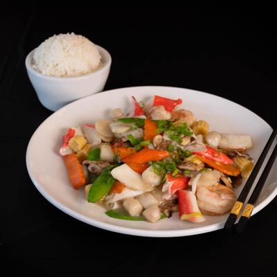 A seafood dish with sauteed lobster, prawns, and veggies, served with rice.