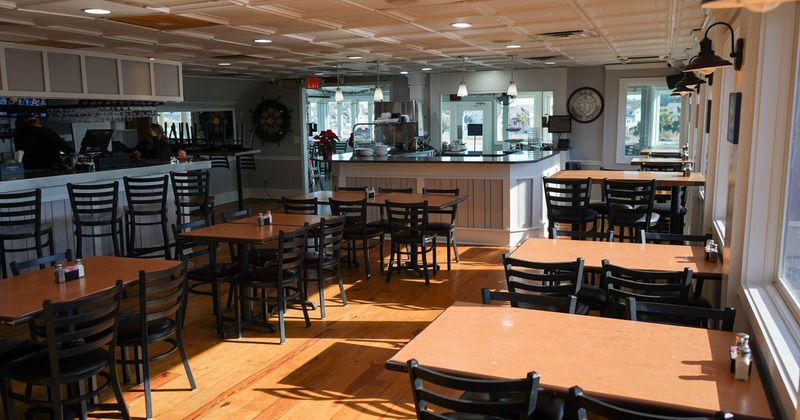 Interior of a sunlit café with wooden tables, black chairs, and a counter