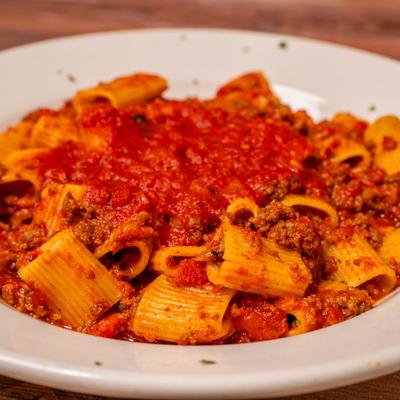 Plate of rigatoni covered in a rich meat sauce.