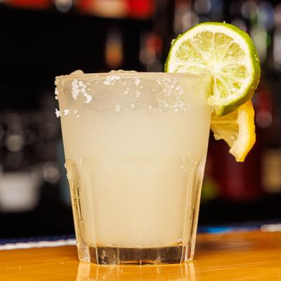Lime margarita in a salt-rimmed glass with citrus garnish.