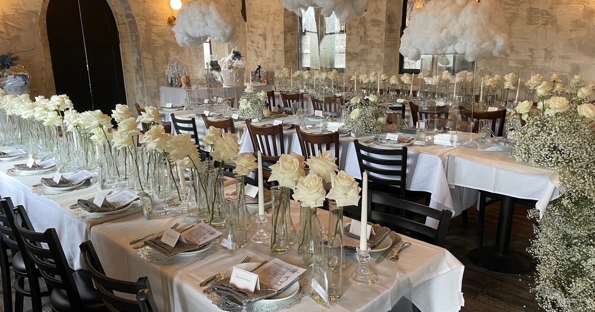 Wedding reception room, long tables with white tablecloths, tableware and floral display