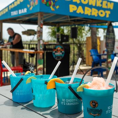 Frozen cocktail buckets lined up on an outdoor table.