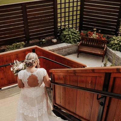 Outdoors, a bride walking down the stairs towards a groom.