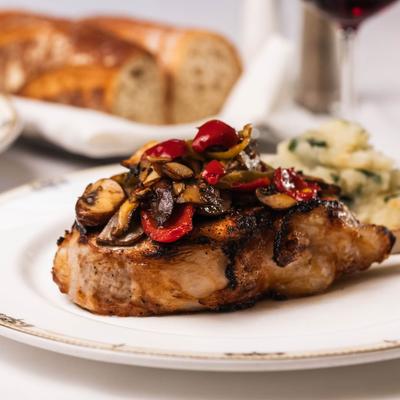 Broiled veal chop topped with roasted vegetables.
