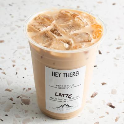 Iced latte in a clear cup on a speckled countertop.