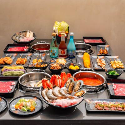Hot pot table spread with seafood, sliced meats, skewers, and broth.
