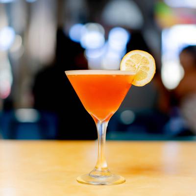 A glass of Cosmopolitan garnished with lemon wheel.