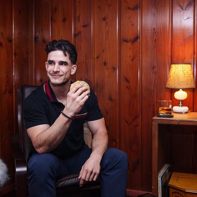 A man sitting down holding a breakfast sandwich before he starts the day.