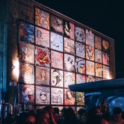 Large outdoor graffiti mural wall above crowd gathering.