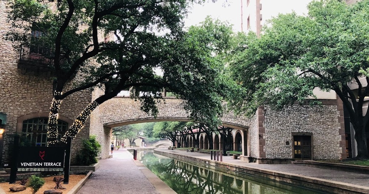 Canal walkway with arched stone bridge and tree-lined area