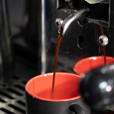 Fresh espresso pouring into a red cup from a coffee machine.