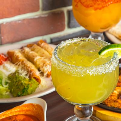 Salt-rimmed margarita beside a plate of Mexican food.