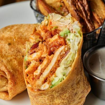 Crispy chicken wrap with lettuce served beside fries and a dipping sauce.
