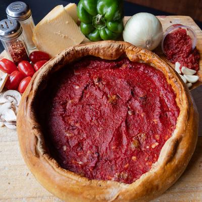 Chicago-style deep-dish pizza surrounded by fresh ingredients.