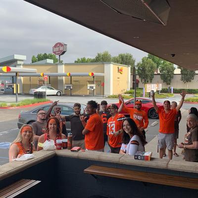 A group of friends in orange shirts cheering in the parking lot