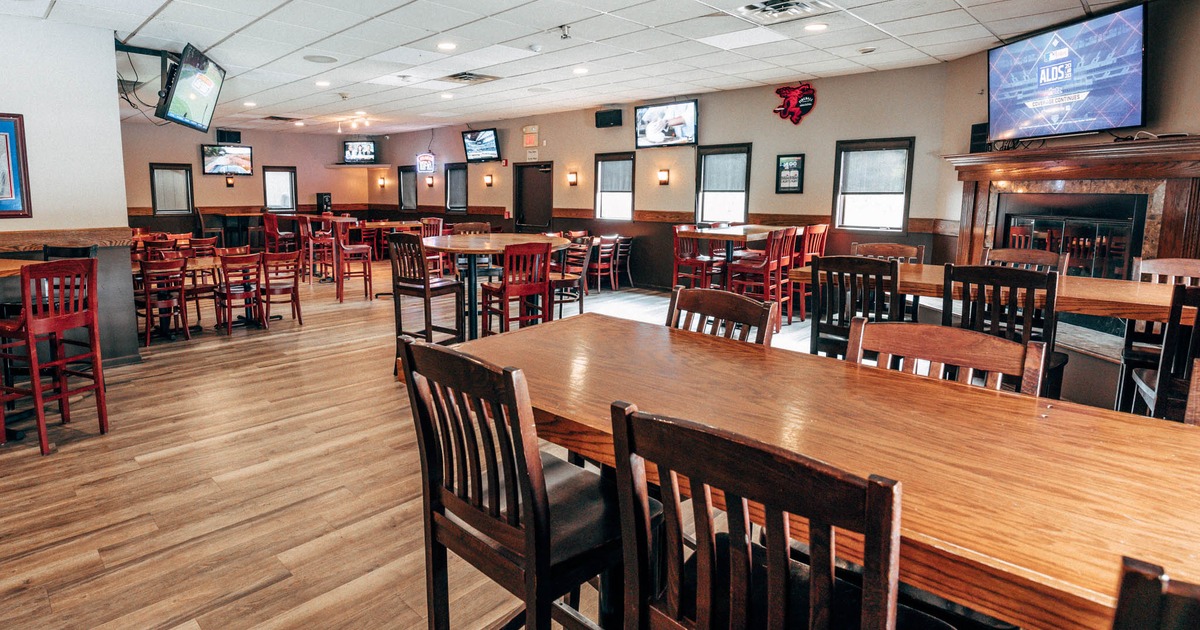 Interior, wooden furniture, TVs, framed artwork, and a rear door with signage