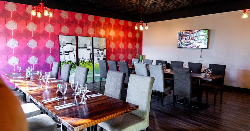Inside, wooden tables, gray chairs, red tree patterned wallpaper, artwork, pendant lights, TV
