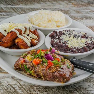 Cuban Chimichurri Steak with sides of rice, beans and fried plantains.