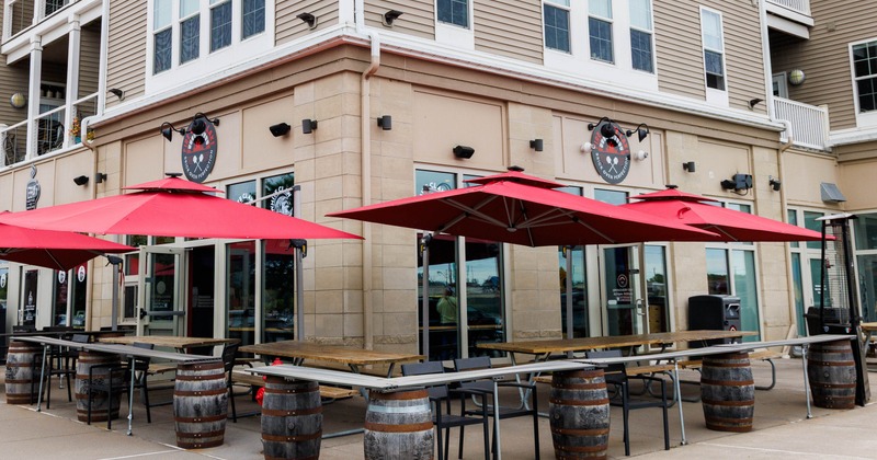 Outside, patio with red umbrellas, wooden tables, barrel tables