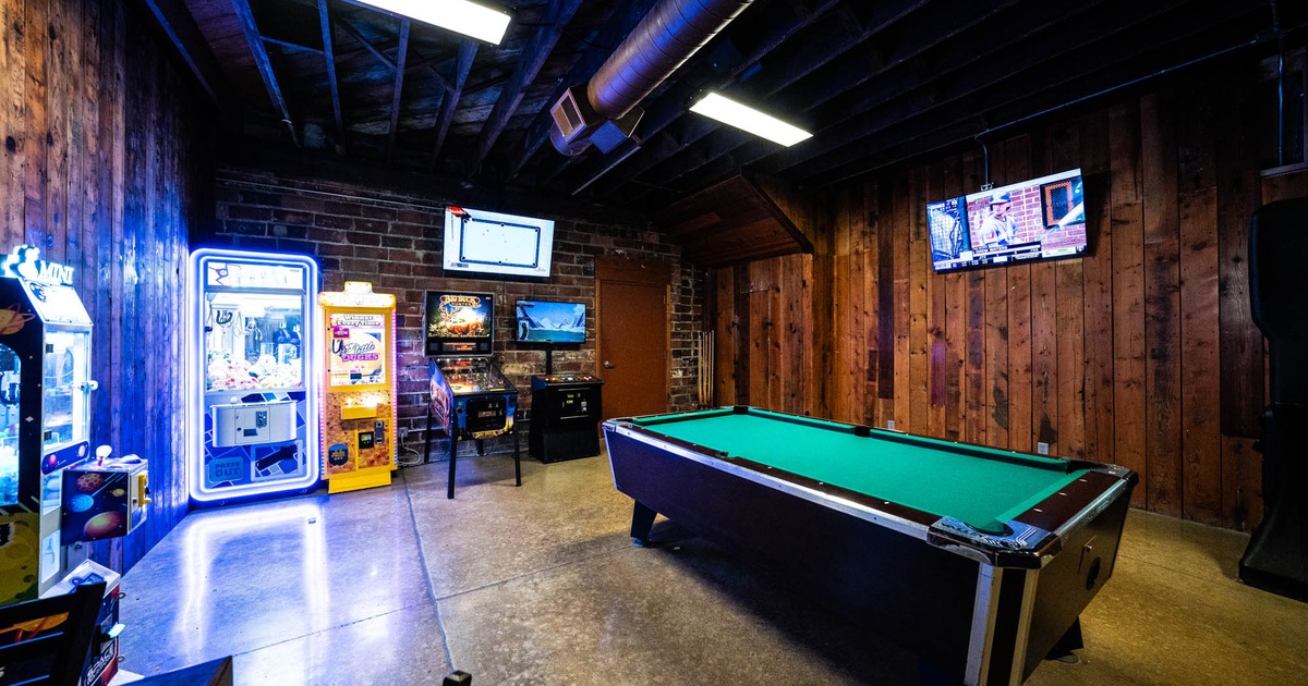 Game room featuring a pool table, arcade machines, pinball, and a wall-mounted TV