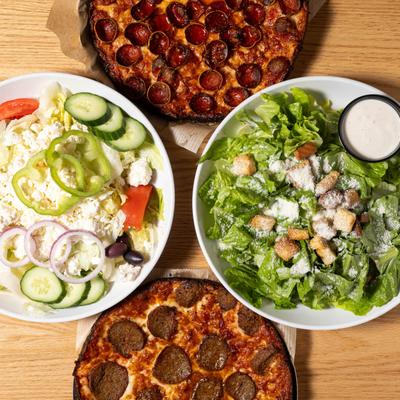 Top view, clockwise motion - pepperoni pizza, Caesar salad, meatball pizza, and Greek salad.