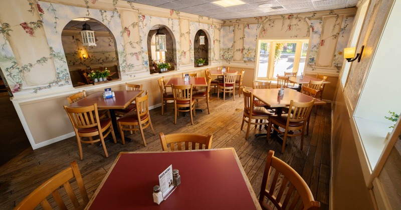 A cozy restaurant interior featuring wooden tables and chairs, floral wallpaper