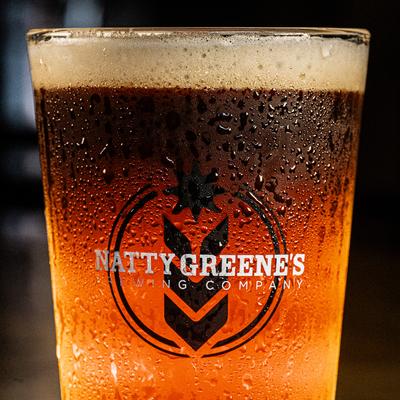 Cold amber beer with condensation in a  branded glass.