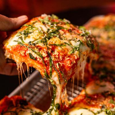 A hand holding a lasagna piece.