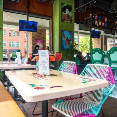 Interior featuring tabale seating and chairs with colorful woven designs.