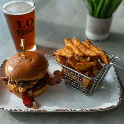A juicy bacon cheeseburger and seasoned fries served with a cold amber beer.