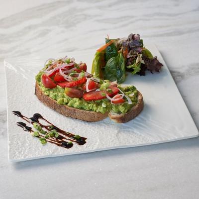 Avocado toast, topped with red onions and tomatoes.
