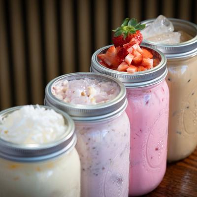 Colorful mason jar drinks lined up on a counter.