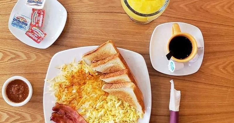 Hash browns, cheese, bacon and toast, a cup of coffee and orange juice, top view