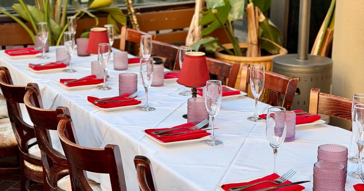 Outdoor dining table dressed with white linens and red accents for a special gathering at Il Sogno Italiano.