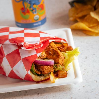 Chicken kabob alomgside a drink in a can and potato chips.