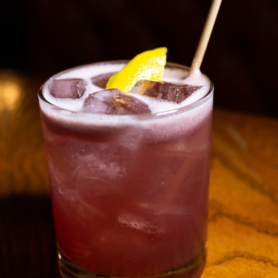 Pink cocktail with ice and lemon wedge