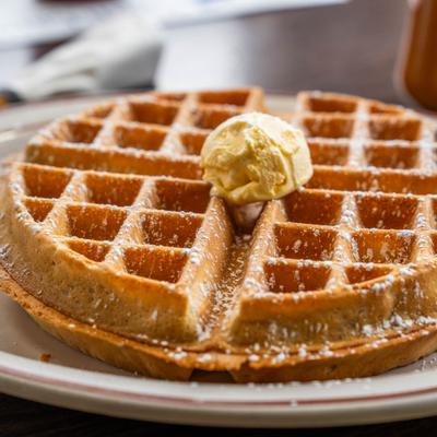 Golden Belgian waffle topped with butter and powdered sugar.