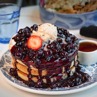 Fluffy blueberry pancakes topped with blueberry compote, ice cream, and a strawberry slice.