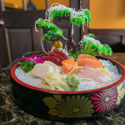 A decorative sushi platter on ice with assorted sashimi, set on a patterned bowl.