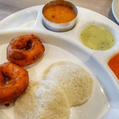 Indian breakfast with steamed rice cakes, lentil fritters, lentil stew, and green chutney.