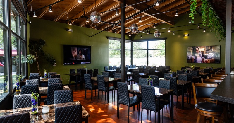 An indoor restaurant dining area with olive green walls, dark tables, and hanging disco balls