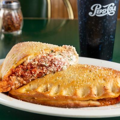 Calzone plate on a table with a cup of soft drink.