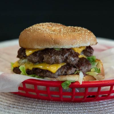 Double cheeseburger with lettuce on a sesame bun.